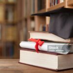 Graduation hat on stack of books and diploma